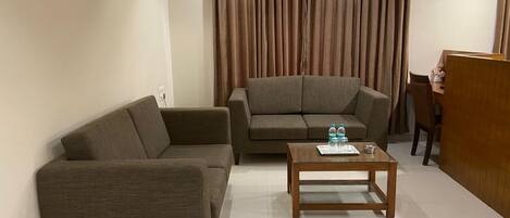 Una sala de estar con dos sofás, una mesa de centro y una cortina.
