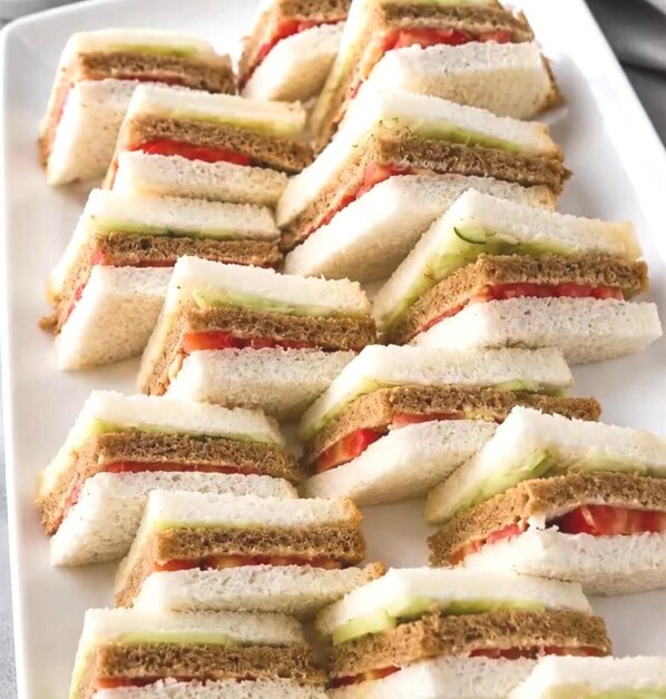 A white rectangular plate with neatly arranged sandwiches.