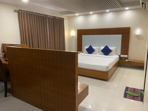 A hotel room with a bed, bedside table, and a wooden partition.