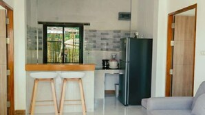 A modern living room with a sofa, a glass coffee table, and a kitchen area in the background. - Garden Villa Green View Central Location (Srithanu Beach)