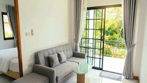A modern room with a sofa, a glass coffee table, and a bed. - Garden Villa Green View Central Location (Srithanu Beach)