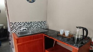 Cocina compacta con encimera de madera, un lavabo y una tetera.