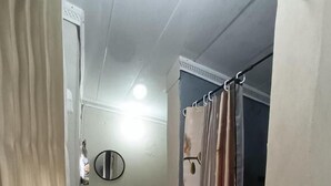 Un pasillo estrecho que conduce a un baño con cortina de ducha, lavamanos y espejo.