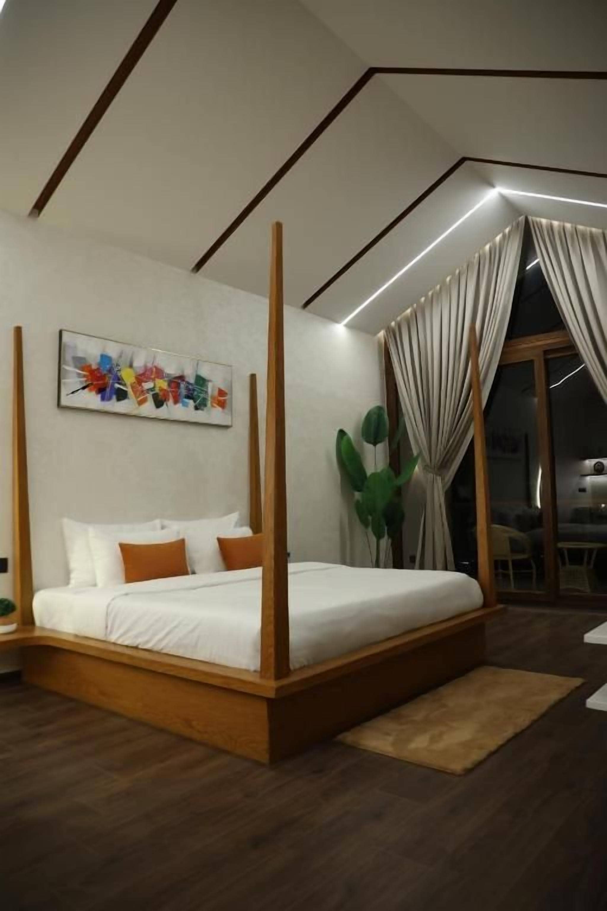 A modern bedroom with a four-poster bed, a large window with curtains, and a painting on the wall.