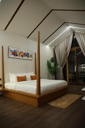 A modern bedroom with a four-poster bed, a large window with curtains, and a painting on the wall.