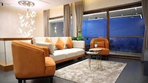 Una sala de estar moderna con un sofá, sillones, una mesa de centro y un ventanal con cortinas.
