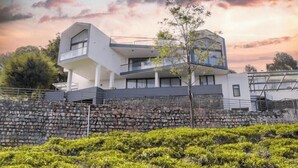Un edificio moderno de dos pisos con techo plano y un muro de piedra en primer plano.