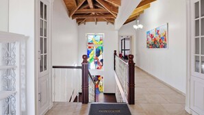 Um corredor com teto de madeira, paredes brancas e um vitral.