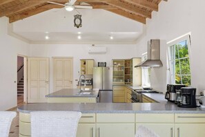 A spacious kitchen with a central island, stainless steel appliances, and a large window providing natural light. - Villa Dama del Mar,, (Cabarete)