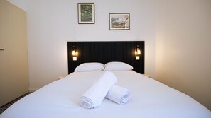 A hotel room with a large bed, two wall-mounted lights, and two framed pictures on the wall. - La Maison Momiji - Elegance and the Art of Living (Tours)