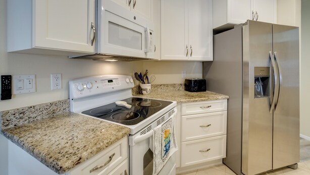 A kitchen with white cabinets, a stainless steel refrigerator, a microwave, and a stove. - 4 Mi to Beaches! Family Getaway w/ Pool in Venice (Venice)