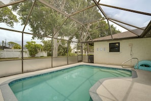 An indoor swimming pool with a glass ceiling, surrounded by trees and a fenced area.