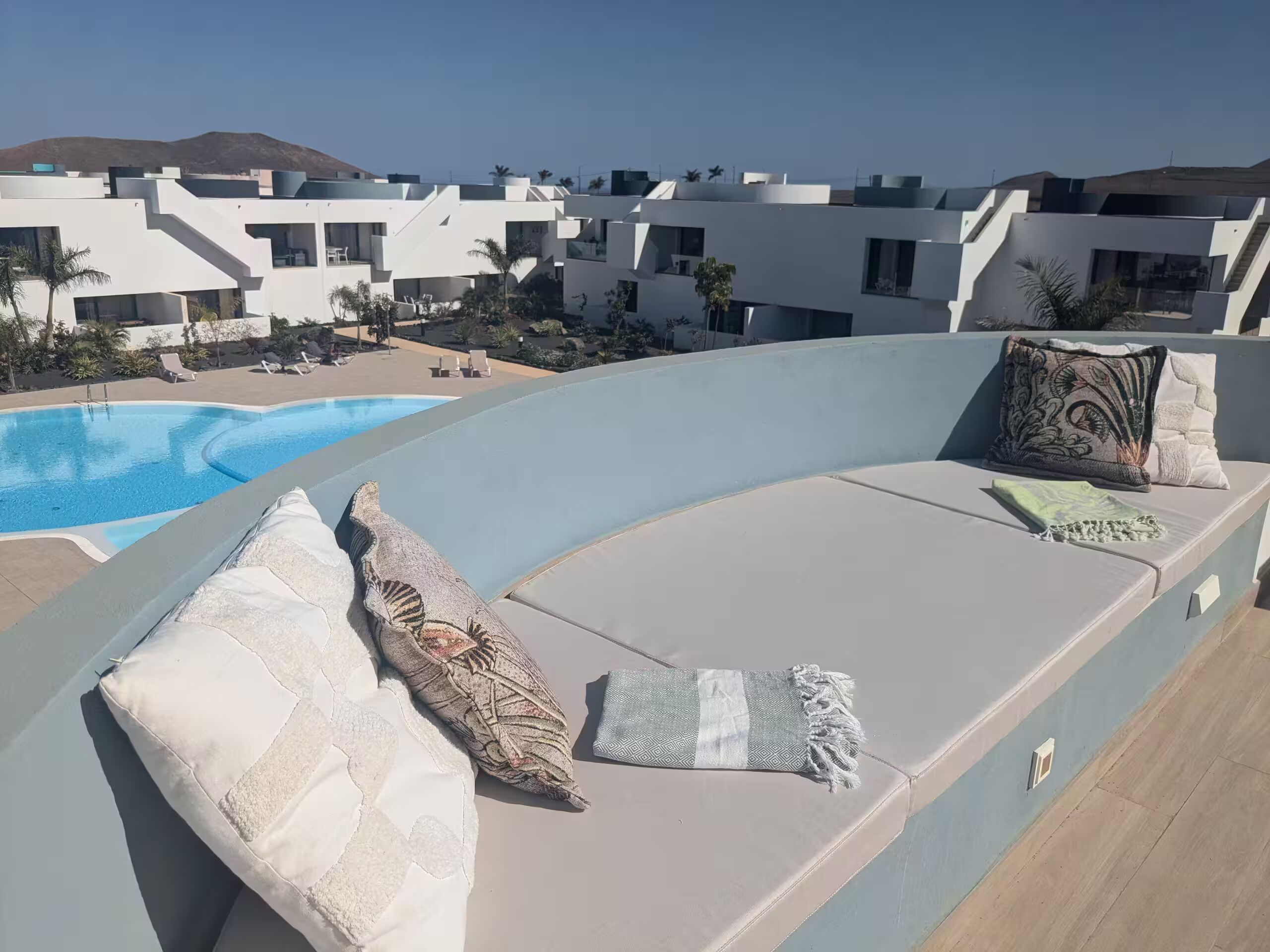 En tagterrasse med pool, udendørs møbler og udsigt til moderne bygninger.