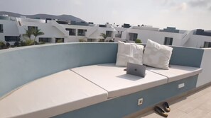 A rooftop terrace with a white sofa, two pillows, and a laptop. - Cozy apartment with a pool in a quiet complex, perfect for a relaxing vacation. (La Oliva)