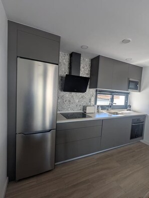 A modern kitchen with a stainless steel refrigerator, a microwave, and a built-in oven. - Cozy apartment with a pool in a quiet complex, perfect for a relaxing vacation. (La Oliva)