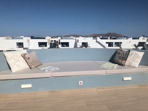 A rooftop terrace with a seating area, a view of the cityscape, and a clear sky. - Cozy apartment with a pool in a quiet complex, perfect for a relaxing vacation. (La Oliva)