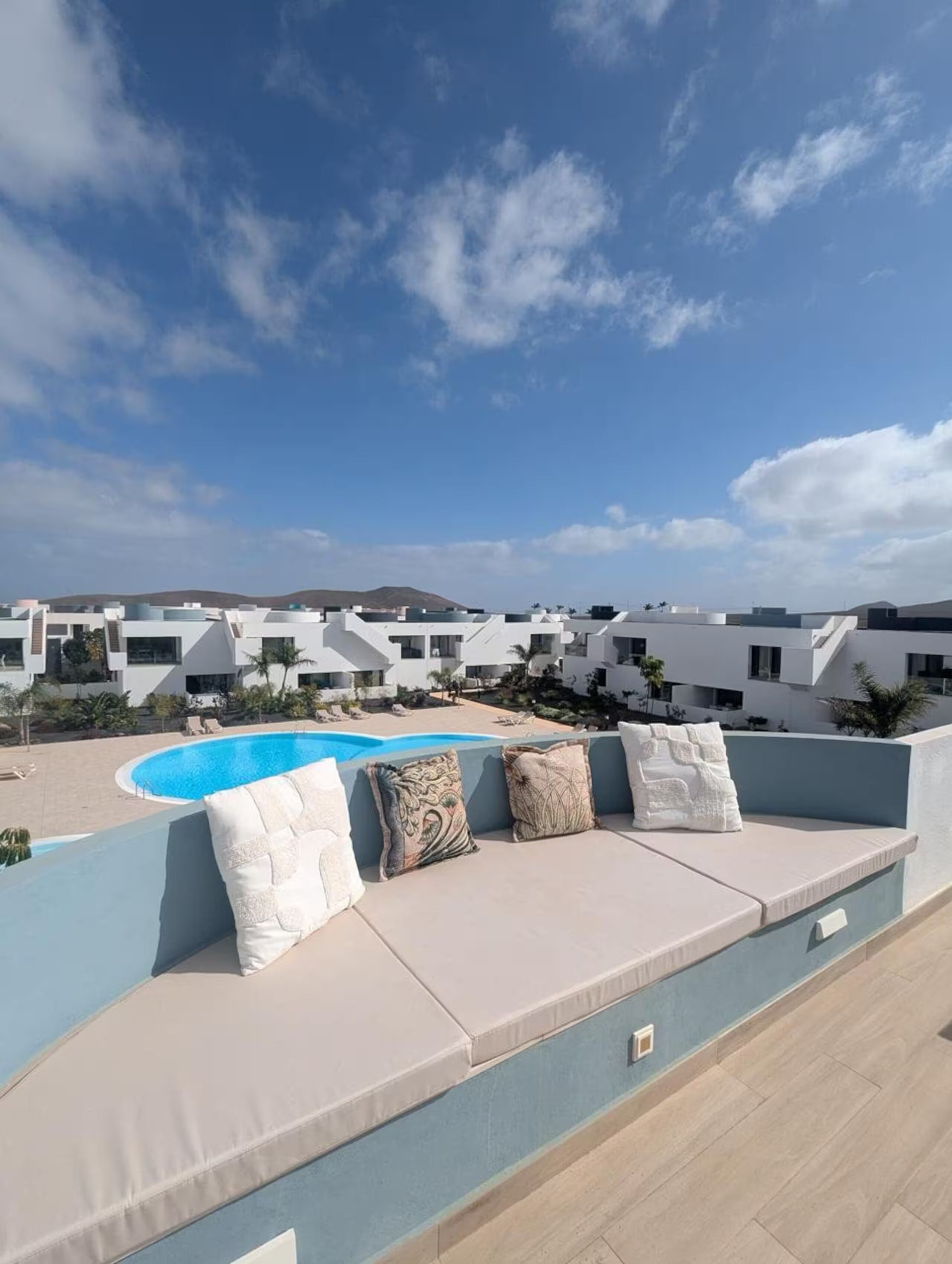 Une terrasse sur le toit avec une piscine, un espace salon extérieur et une vue sur des bâtiments modernes.
