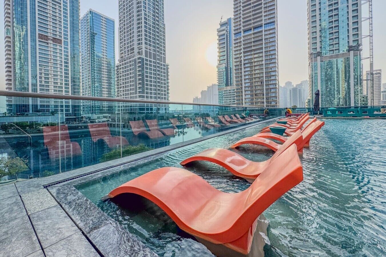 Een waterattractie met oranje glijbanen, gelegen in een moderne stedelijke omgeving met hoge gebouwen op de achtergrond.
