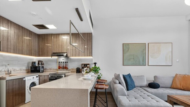 A modern kitchen with a central island, built-in appliances, and a dining area with a sofa and coffee table. - Relaxing City Escape in JLT (Dubai)