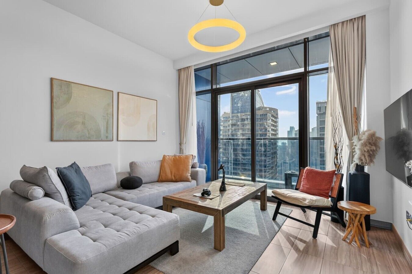 Ein modernes Wohnzimmer mit einer Couch, einem Couchtisch und Blick auf die Stadt durch große Fenster.