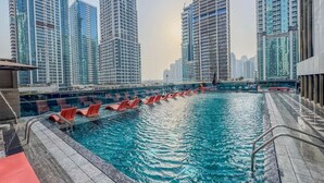 A swimming pool with red chairs and a view of high-rise buildings. - Relaxing City Escape in JLT (Dubai)