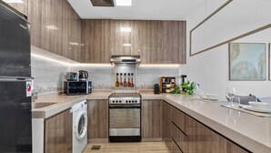 A modern kitchen with a built-in washing machine, a stove, and a microwave. - Relaxing City Escape in JLT (Dubai)