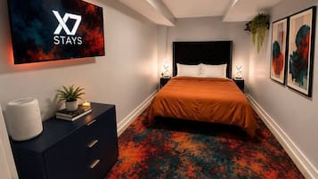 Een hotelkamer met een bed, nachtkastje, televisie aan de muur en een decoratieve plant.