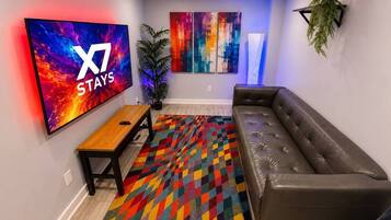 Een moderne woonkamer met een grote flatscreen televisie, een bank, een salontafel en een kleurrijk vloerkleed.