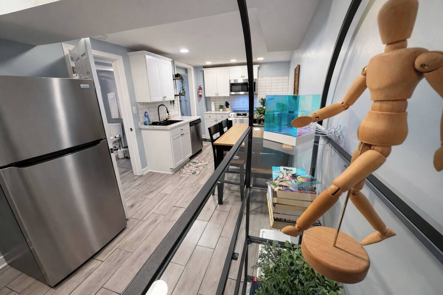 Een moderne keuken met een roestvrijstalen koelkast, witte kasten en een glazen eettafel.