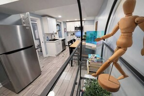 Eine moderne Küche mit Edelstahl-Kühlschrank, weißen Schränken und einem Esstisch aus Glas.