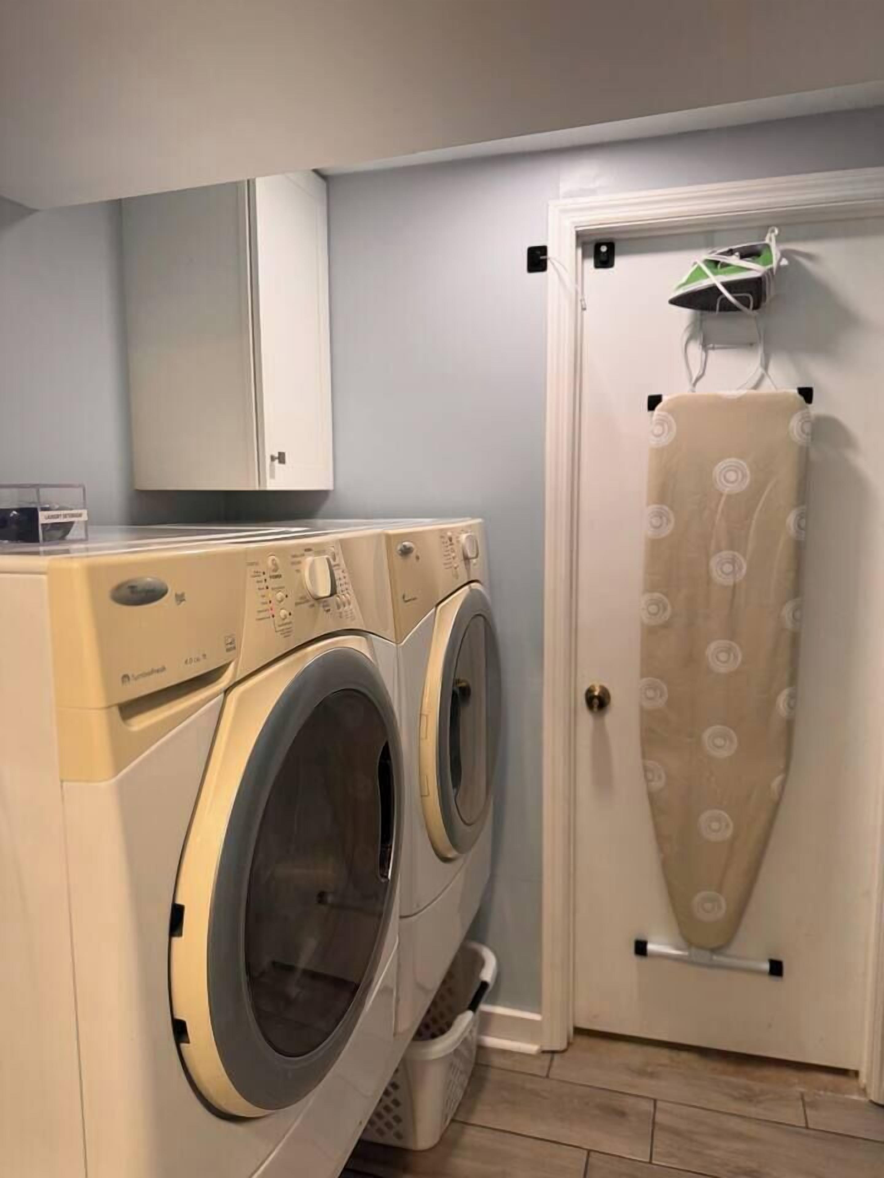 Een wasruimte met twee wasmachines, een droogrek en een kast.