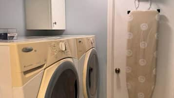Een wasruimte met twee wasmachines, een droogrek en een kast.