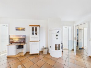 Ett rum med en tv, ett skåp, en varmvattenberedare och en dörr som leder till ett annat rum.