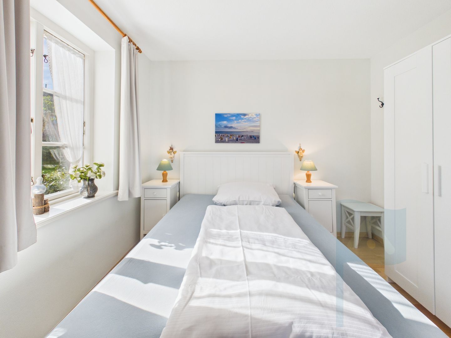 Une chambre à coucher comprenant un lit, des tables de chevet, une fenêtre avec des rideaux, un tableau accroché au mur et une petite table.