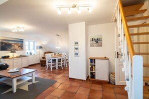 Ein kompakter Wohnbereich mit Essplatz, Küche, Treppe und Bücherregal.