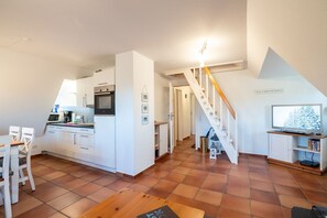 Ein kompakter Wohnraum mit Küche, Essbereich und einer Wendeltreppe zu einem Schlafzimmer im oberen Bereich.