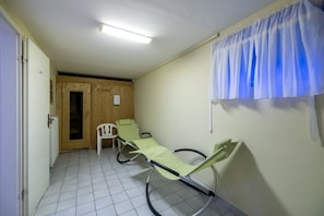Ein steriler Raum mit einem Bett, einem Stuhl und einer Holztür.