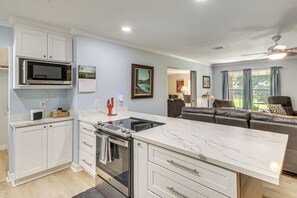 A modern kitchen with a central island, built-in oven, and microwave. There is a seating area with a sofa and a dining table. - Family Getaway w/ Pool on 8 Acres in Carriere! (Carriere)