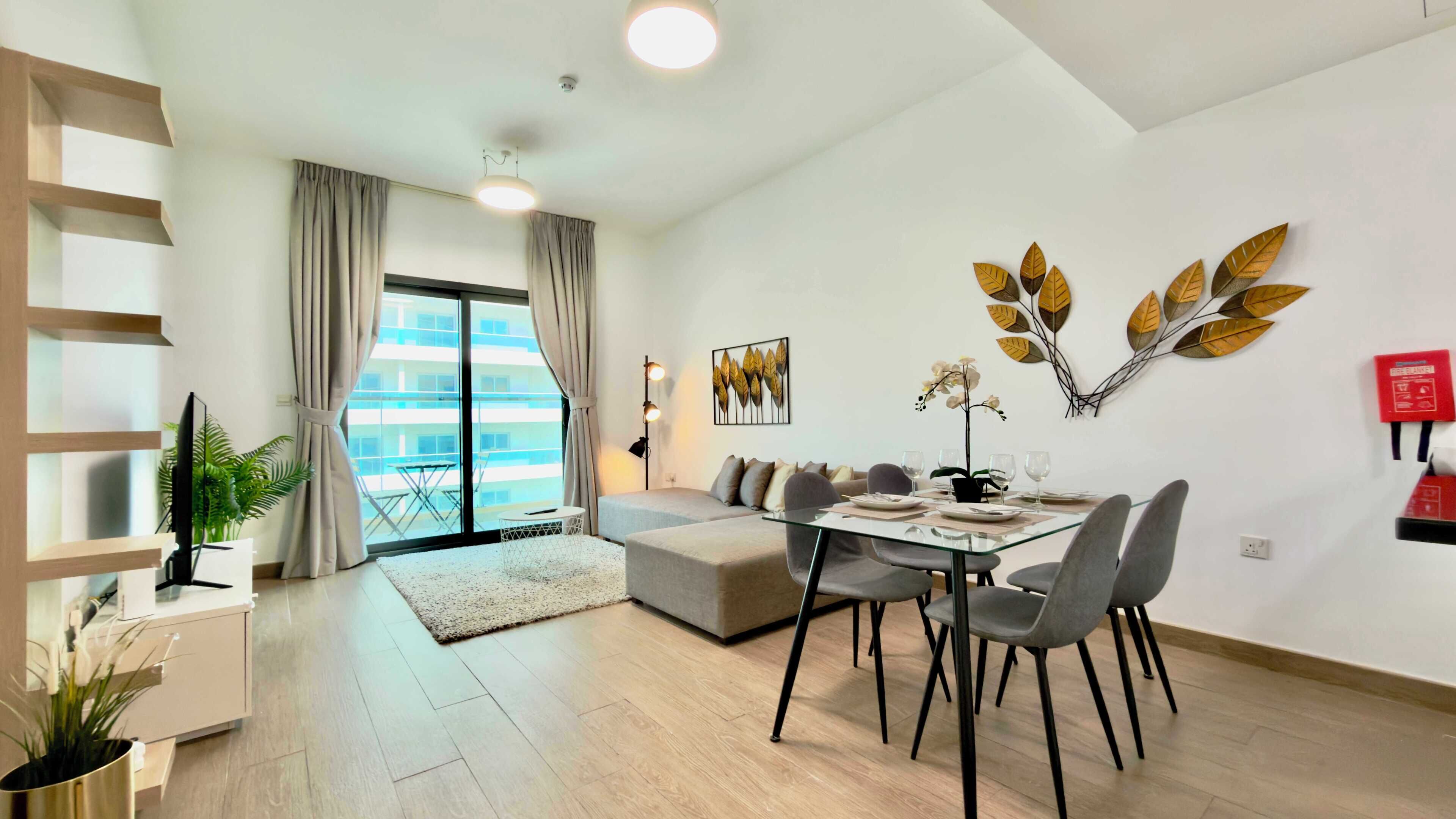 Una sala de estar moderna con comedor, sofá, televisor y un gran ventanal con cortinas.