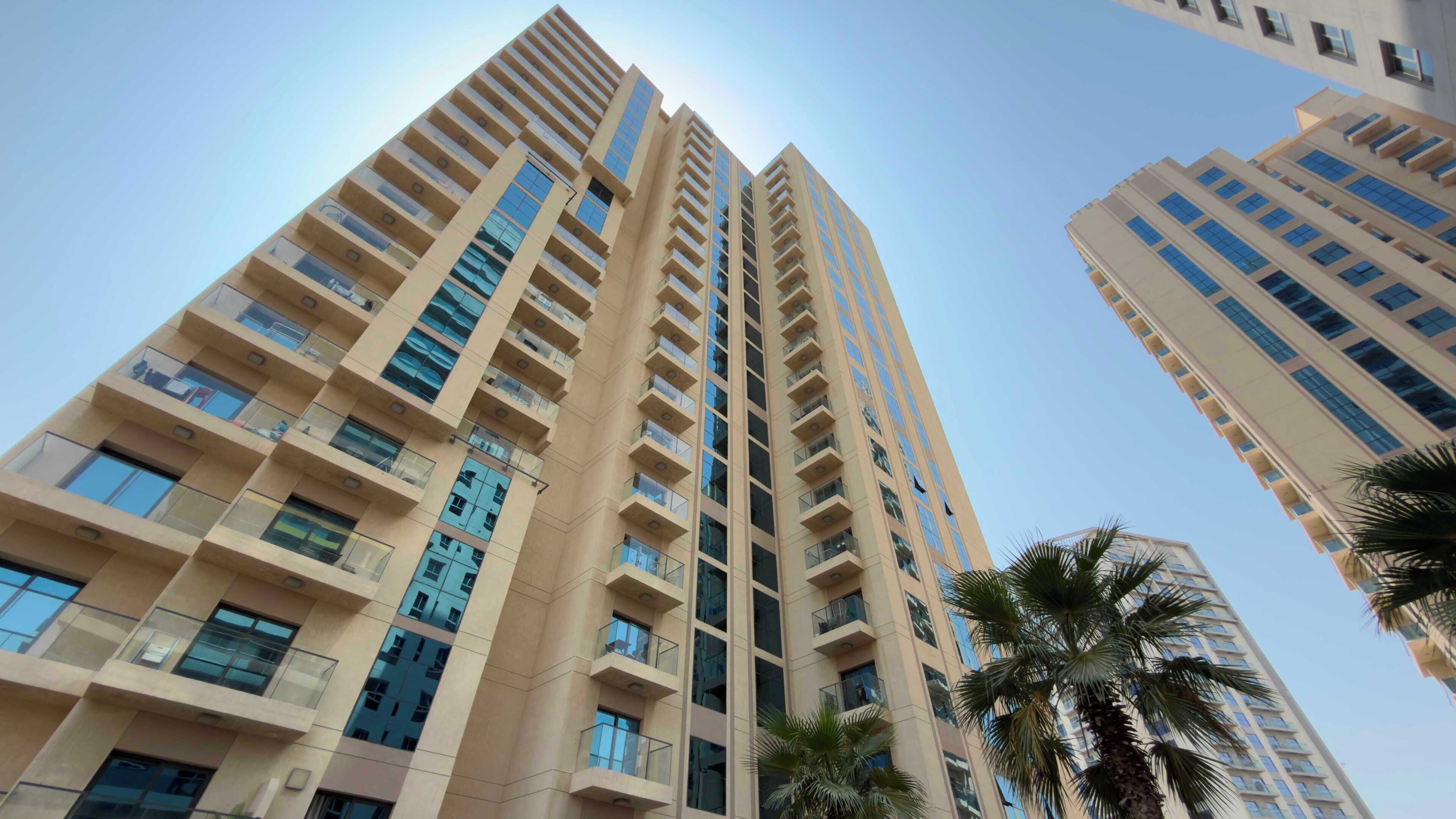 A high-rise building with multiple balconies and a clear sky.