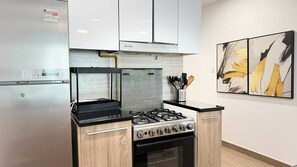 Uma cozinha com fogão a gás embutido, forno e geladeira de aço inoxidável.