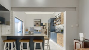 Cozinha moderna com ilha central, banquetes e vista para a sala de jantar.