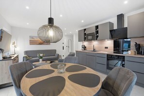 A modern kitchen with grey cabinets, a built-in oven, and a black range hood. - Küstenkoje - Küstenkoje: New vacation rental with a garden in Norddeich (Norden)