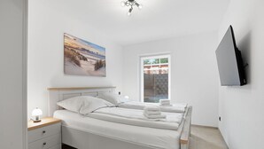 Et soveværelse med seng, natbord, lampe og et billede på væggen.