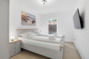 A bedroom with a bed, bedside table, lamp, and a painting on the wall. - Küstenkoje - Küstenkoje: New vacation rental with a garden in Norddeich (Norden)