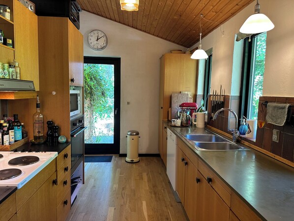 A kitchen with wooden cabinets, a stainless steel sink, and a clock on the wall.