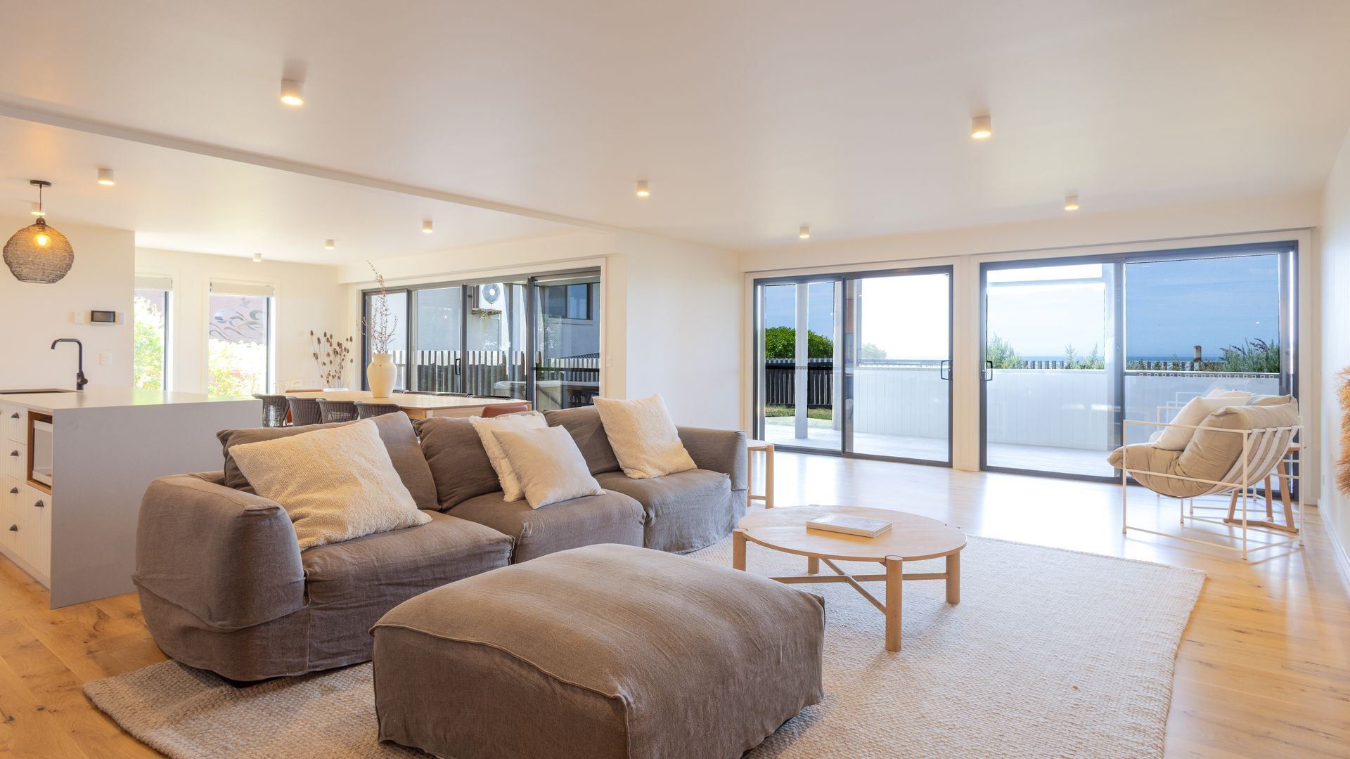 A spacious living area with a sofa set, a coffee table, and a view of the outdoors through large sliding doors.