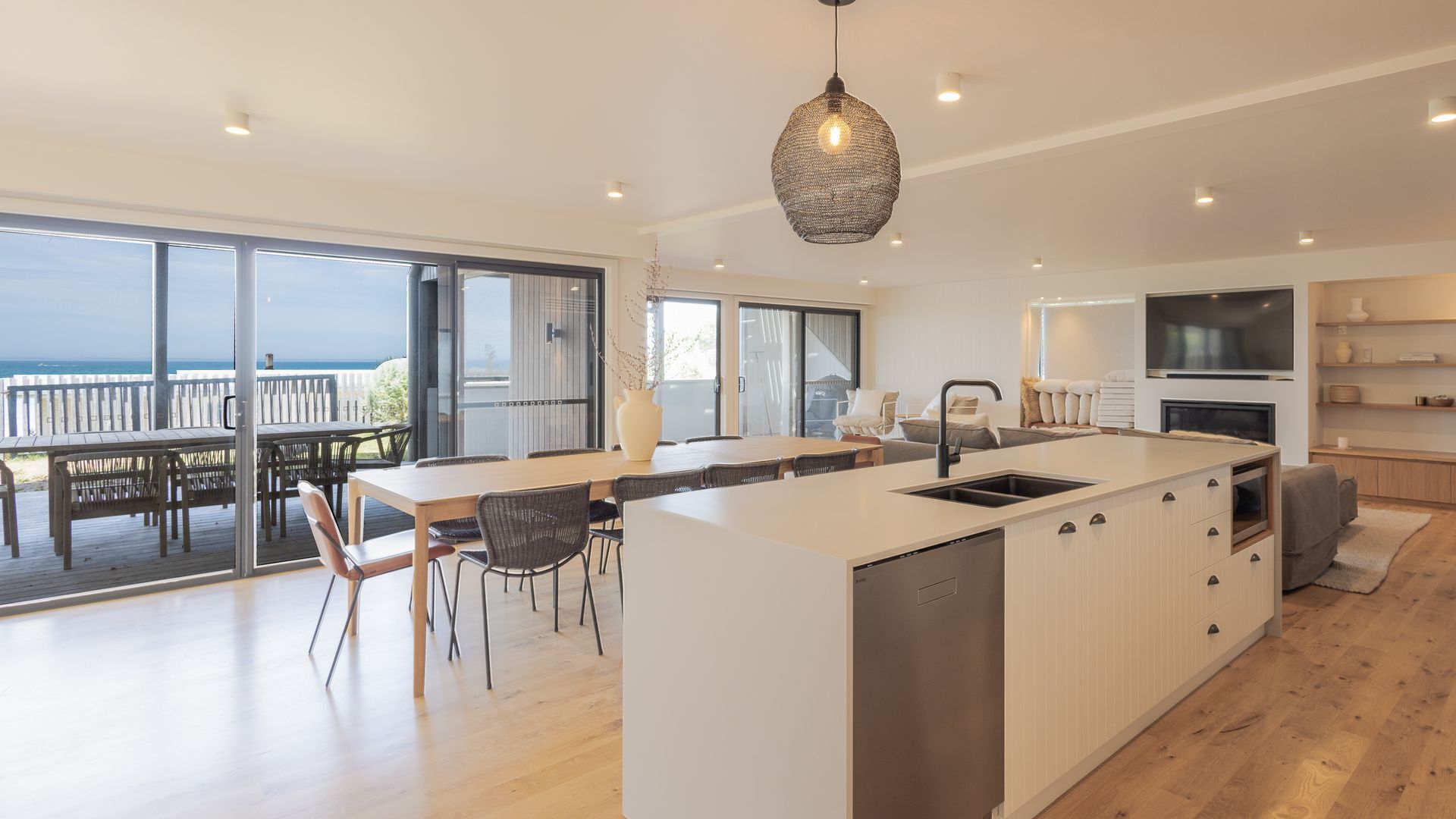 A modern kitchen with a large island, a dining area with a view, and a living space with a flat-screen TV.