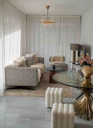 A modern living room with a sofa, armchair, glass coffee table, and decorative items.