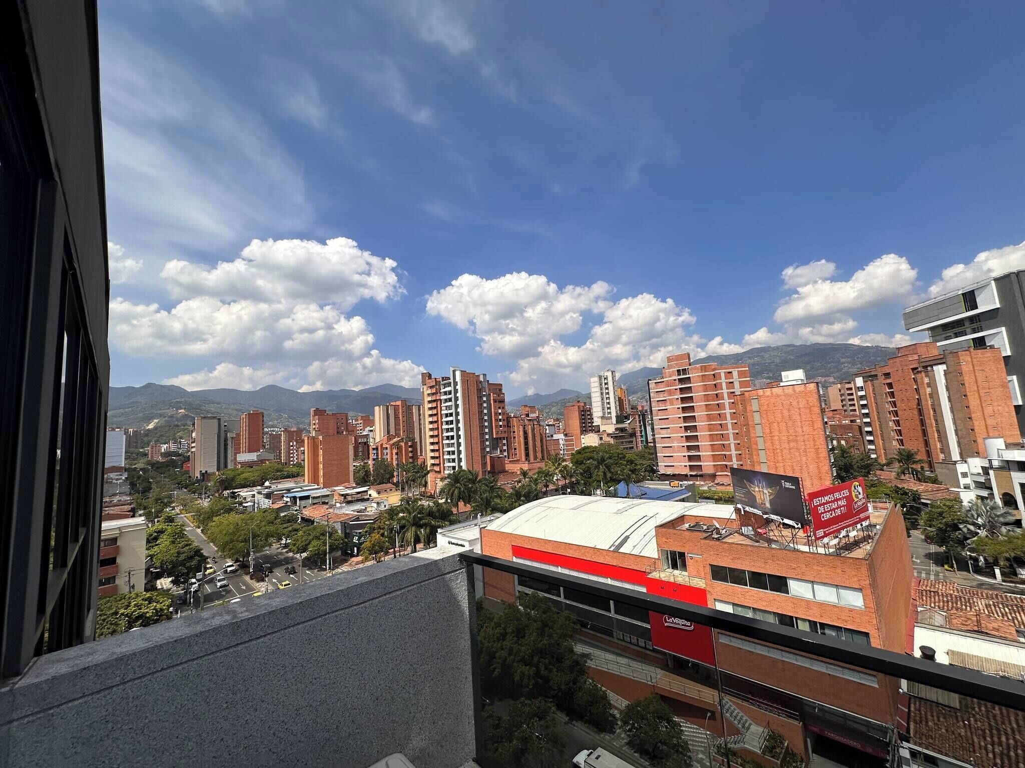 A cityscape with high-rise buildings, a clear sky, and mountains in the background.